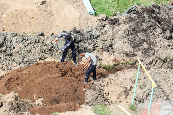 Los trabajadores entierran la trinchera con arena . — Foto de Stock