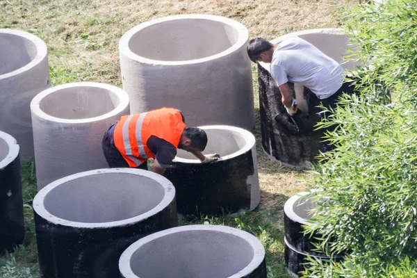 Los trabajadores ponen una capa de impermeabilización en anillos de hormigón . — Foto de Stock