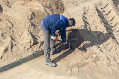 Bir kürek kazma kum ile işçi.