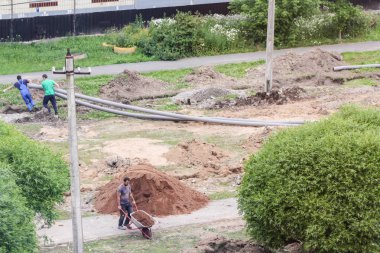 İşçiler hendek boyunca boru sürükleyin.
