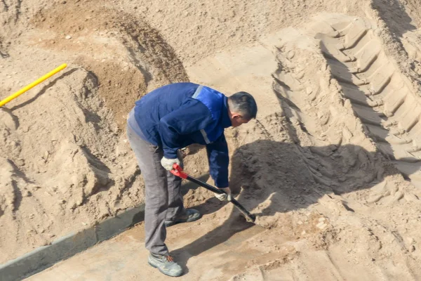 Bir kürek kazma kum ile işçi.