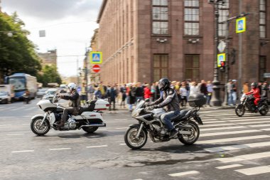 Bir grup motosikletli seyircilerin yanından geçiyor..