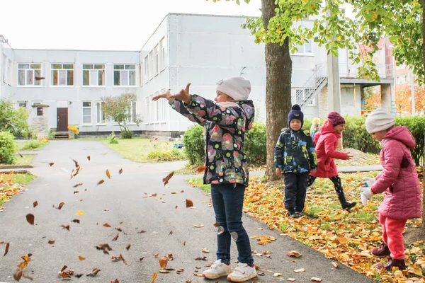 Anak-anak melemparkan daun musim gugur ke udara . — Stok Foto