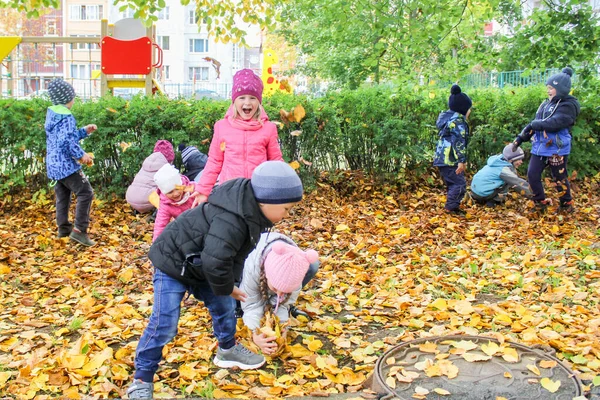Anak-anak bermain dengan dedaunan musim gugur . — Stok Foto
