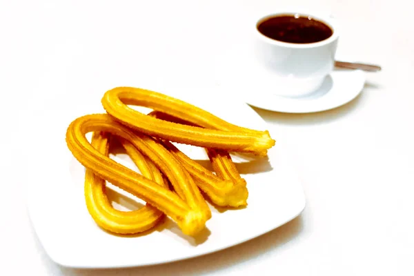 Churros op een bord en een kopje chocolade op witte achtergrond — Stockfoto