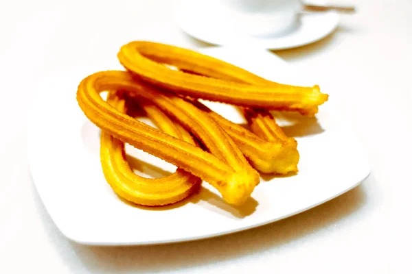 Churros traditional spanish breakfast on a plate on white background
