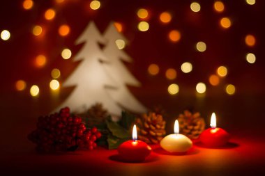 Christmas candles and ornaments over red dark background with lights clipart
