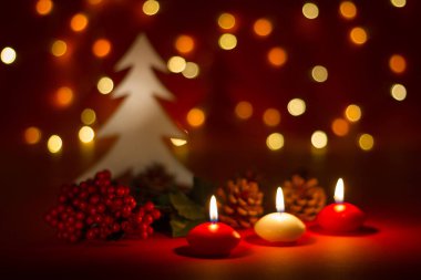 Christmas candles and ornaments over red dark background with lights clipart