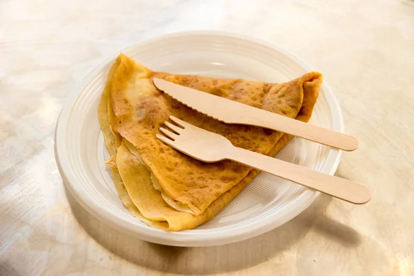 A crepe with wooden fork and knife under natural light