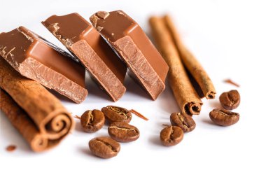 Lezzetli sütlü çikolata tatlı kahve ve tarçın taneleri ile izole üzerinde beyaz arka plan sopa