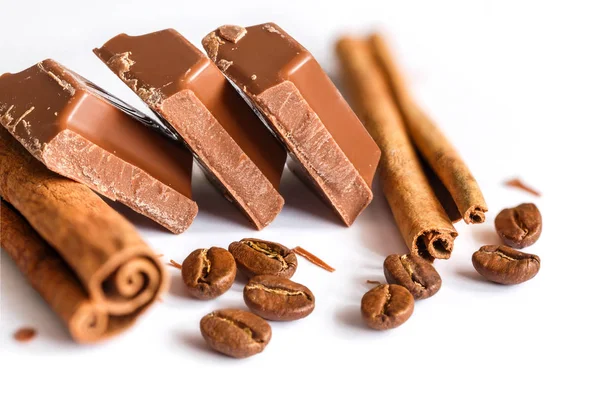 Lezzetli sütlü çikolata tatlı kahve ve tarçın taneleri ile izole üzerinde beyaz arka plan sopa