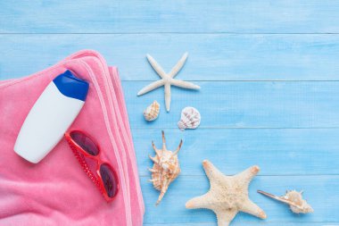 güneş gözlüğü, havlu ve yaz tatil zaman arka plan için ışık mavi ahşap tahta katta güneş kremi