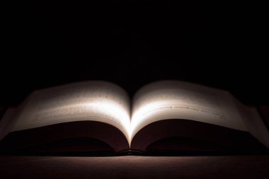 koyu arka plan üzerinde soyut açık kitap karşıyageldiklerinde ile ışıklı
