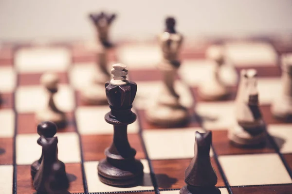 Чорний проти білих шахових фігур на шаховій дошці — стокове фото