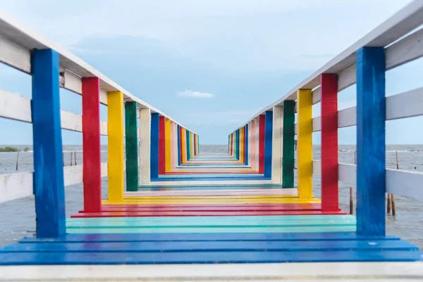 Bunte Regenbogenholzbrücke ins Meer mit blauem Himmel — Stockfoto