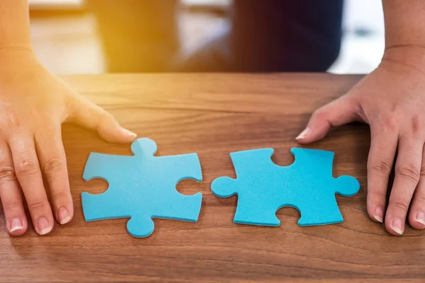 Woman hand connecting two pieces of jigsaw puzzle — Stock Photo, Image