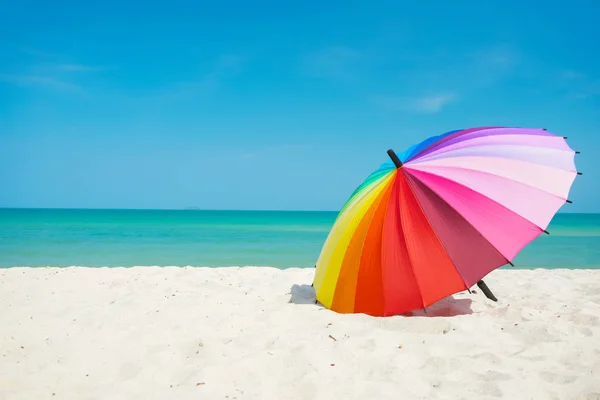 Paraguas arco iris en la arena de la playa — Foto de Stock