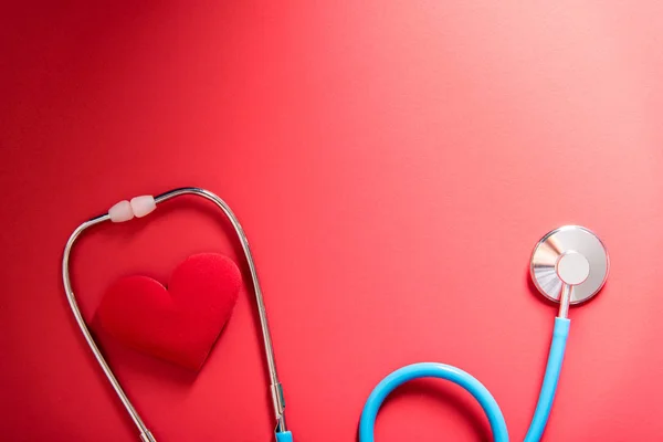 Red heart and stethoscope on red background — Stock Photo, Image