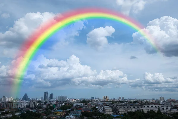 Regenbogen im bewölkten Himmel über der Stadt — Stockfoto