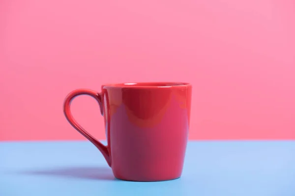 Röd kaffekopp på blått och rosa papper, minimal stil bakgrund — Stockfoto