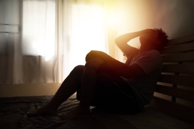 siluet içinde umutsuz adam hea elleri ile yatakta oturan