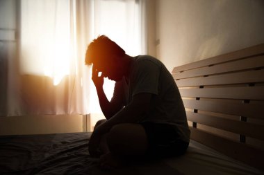 siluet içinde umutsuz adam hea elleri ile yatakta oturan