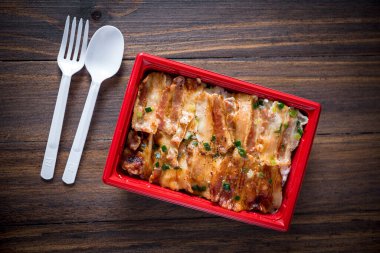 Kırmızı kutuda pirinç, kızarmış tuzlu dilimlenmiş domuz eti, yiyecek teslimatı.