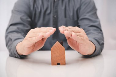İşadamı eli ahşap ev modeli, ev sigortası konsepti.