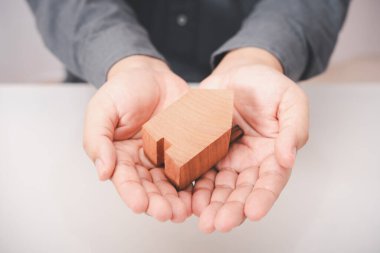 Ahşap ev modeli iş adamı elinde.