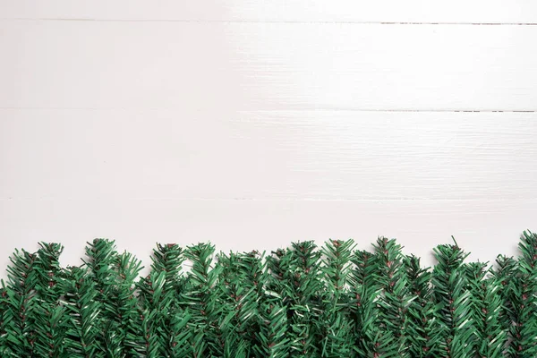 白色木制背景的人造圣诞树叶子装饰 — 图库照片