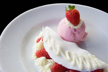 Beyaz tabakta dondurma ve koyu arkaplanda çilekli tapyoka.