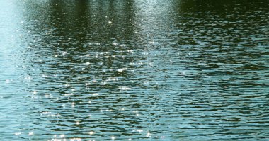 Gölde dalgalanmalar olan su yüzeyi. Duvar kağıtları, posterler ve arka planlar için.