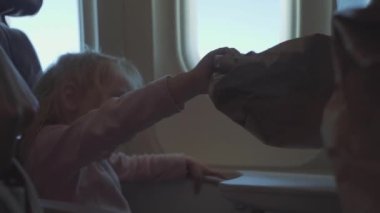 Çocuk, COVID-19 salgını sırasında bir uçağa maske takarak biner ve bir albüm çizer.