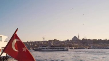 İstanbul 'da Haliç Koyu' ndaki bir gemide Türk bayrağı dalgalanırken, Rustem Paşa Camii üzerinde güneşli bir günde arka planda martılar daireler çiziyor..