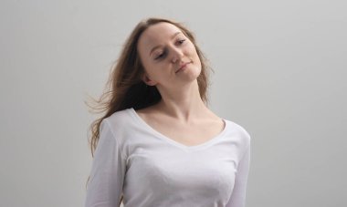 Kendine güvenen genç bir kadın kendisine hayran. O, en iyisi, narsisizm ve kendine hayranlık duyduğundan emin. Gri arka plan, stüdyo