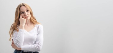 Stüdyoda beyaz arka planda poz veren genç, sıkılmış kadın, kopyalama alanı