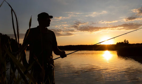 Αλιέων Σιλουέτα Στο Ηλιοβασίλεμα Στέκεται Καλάμι Αλιείας Στη Λίμνη Ακτίνες — Φωτογραφία Αρχείου