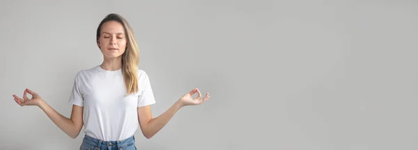 Mein Körper ist eine Festung. Ruhige modische junge Europäerin mit blonden Haaren, mit geschlossenen Augen und entspanntem Gesichtsausdruck, die Hände in Zen-Geste spreizend — Stockfoto