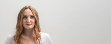 Beyaz tişört giyen, beyaz tişörtlü, sakince ve dikkatlice kameraya bakan, gri arka planda, uzun altın saçlar, kopya alanı, afiş...