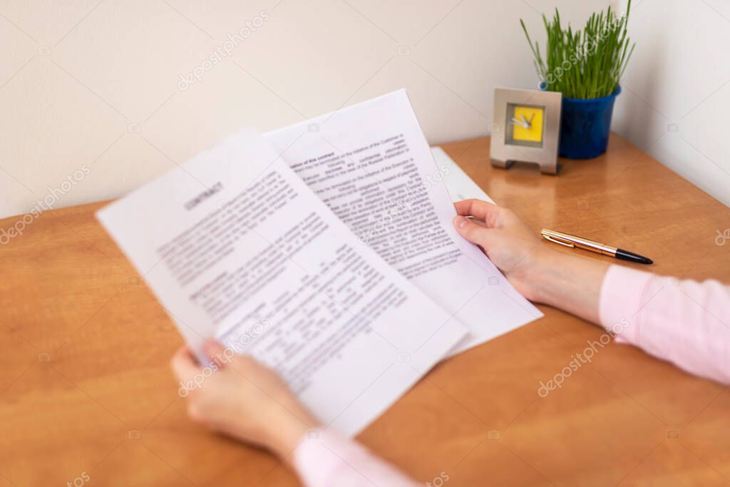 Close up hand business woman at the table in office. Concept of business contract studying reading and signing, business office