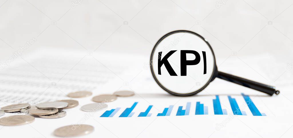KPI Key Performance Indicator text acronym word throgh magnifying glass lens on office desk table. Business KPI concept