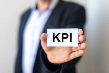 KPI kısaltması Anahtar Performans Göstergesi Kağıt çıkartması üzerindeki metin metni, işadamı eli