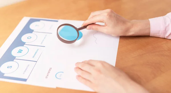 Strength Weaknesses Opportunities Threats Analysis Evaluation Strategy Concept. blue SWOT chart on office table with female hands with pen, marketing strategy, business