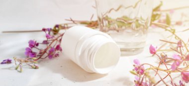 Bir kavanoz hap, bir bardak su ve ot, beyaz arka planda haplar yerine sağlık ve şifa kavramı, şifalı bitkiler, tıbbi, pankart.