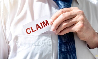 İş adamı elinde elinde yazılı bir kart tutuyor. Dava açıyor ve dava açıyor. Takım elbise giyiyor.