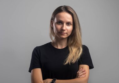 Güzel, genç, dost canlısı ve kendine güvenen bir kadın portresi. Sakince kameraya bakıyor. Stüdyo çekimi, gri arkaplanda izole edilmiş.