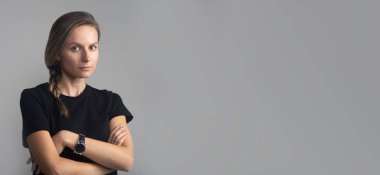 Stüdyo başı ve omuz portresi. Gri, ciddi bir kadının doğrudan kameraya bakması. Siyah tişört, fotokopi alanı, afiş.