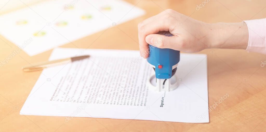 close up woman hand hold blue stamp while signing and stamping contract, make investment, taking insurance, writing will testament, hand with stamp close up, banner