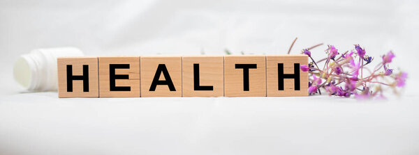 Здоровье слово, сделанное на деревянных кубических блоков с травами и банка таблеток на белом фоне. Концепция здравоохранения. banner