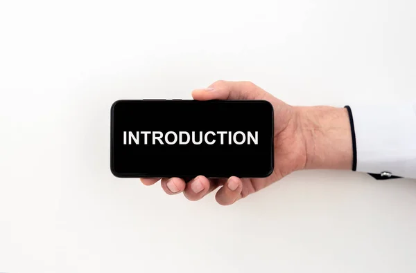 Introduction word inscription on white paper, phone screen in male hand over white background